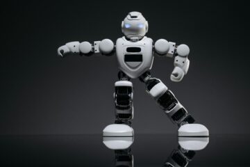 Close-up of a white toy robot with glowing eyes on a reflective black surface.